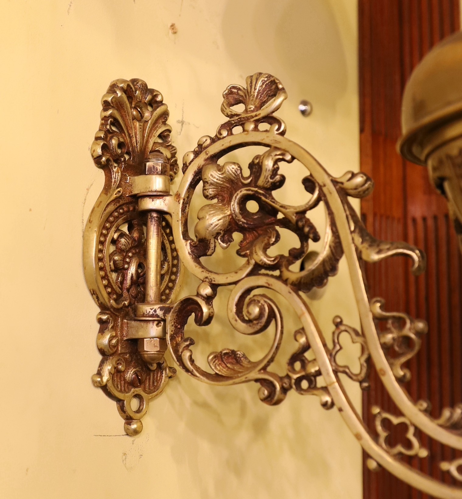 A pair of Victorian brass wall mounted oil lamps, with swivelling foliate pierced branches and aubergine glass shades, height overall 40cm